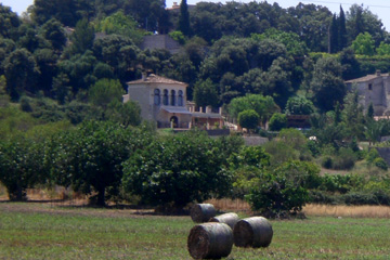 Villa in der Landschaft von Mallorca und davor die zusammen gerollten Strohballen von der Getreideernte.