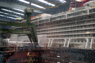 Kran Steinkauz beim Bau von dem Kreuzfahrtschiff in der Werft. Hier sieht man auf dem Bild die Seitenansicht von dem Kreuzfahrtschiff das da gerade im Bau ist.